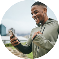 Person smiling while using their smartphone outside